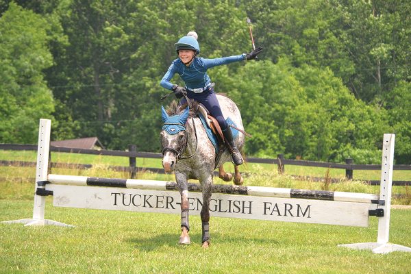 A young equestrian jumping her pony.