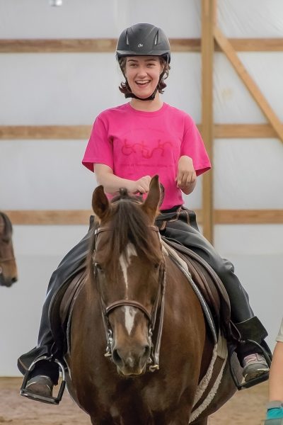 A student smiles aboard a Morgan gelding